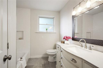 Example of a mid-sized classic 3/4 white tile and subway tile ceramic tile, gray floor and single-sink bathroom design in New Orleans with raised-panel cabinets, white cabinets, a two-piece toilet, gray walls, an undermount sink, quartz countertops, gray countertops, a niche and a freestanding vanity