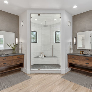 Corner shower - large contemporary master gray tile and porcelain tile porcelain floor and beige floor corner shower idea in Salt Lake City with flat-panel cabinets, medium tone wood cabinets, a one-piece toilet, white walls, an undermount sink, quartzite countertops, a hinged shower door and gray countertops