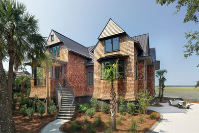 Photo of a large beach style two-storey brown house exterior in Charleston with wood siding, a gable roof and a metal roof.