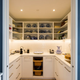 Cette image montre une arrière-cuisine design en U de taille moyenne avec un évier encastré, des portes de placard blanches, un plan de travail en quartz modifié, une crédence blanche, une crédence en carreau de porcelaine, un sol en bois clair et un sol gris.