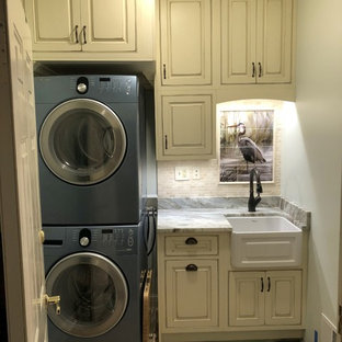 Inspiration for a small nautical single-wall separated utility room in Baltimore with a belfast sink, beaded cabinets, distressed cabinets, granite worktops, green walls, ceramic flooring, a stacked washer and dryer, brown floors and brown worktops.