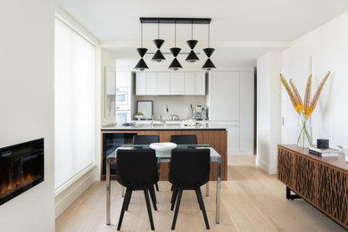 Example of a mid-sized minimalist galley light wood floor eat-in kitchen design in Vancouver with an undermount sink, flat-panel cabinets, white cabinets, quartz countertops, white backsplash, quartz backsplash, paneled appliances, an island and white countertops