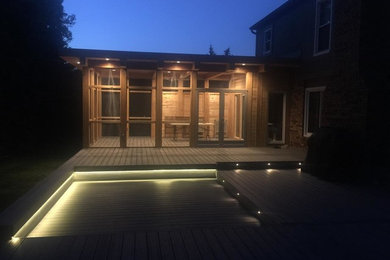 Example of a large minimalist backyard deck design in Other with a roof extension