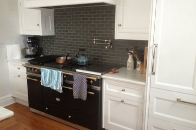Inspiration for a timeless medium tone wood floor and brown floor kitchen remodel in Chicago with recessed-panel cabinets, white cabinets, marble countertops, blue backsplash, ceramic backsplash and black appliances