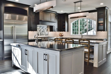 Enclosed kitchen - large transitional l-shaped dark wood floor enclosed kitchen idea in DC Metro with an undermount sink, dark wood cabinets, white backsplash, subway tile backsplash, stainless steel appliances, two islands and shaker cabinets