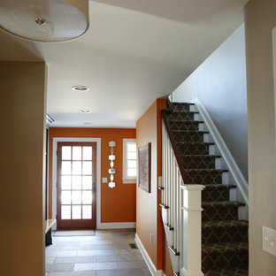 На фото: со средним бюджетом фойе среднего размера в классическом стиле с оранжевыми стенами, полом из сланца, одностворчатой входной дверью и входной дверью из темного дерева