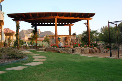 Mid-sized elegant backyard stone patio kitchen photo in Dallas with a pergola