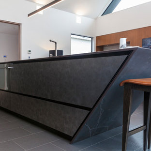 На фото: с высоким бюджетом линейные кухни среднего размера в современном стиле с кладовкой, врезной раковиной, черными фасадами, столешницей из плитки, черным фартуком, фартуком из керамической плитки, техникой из нержавеющей стали, полом из керамической плитки, островом, серым полом и черной столешницей