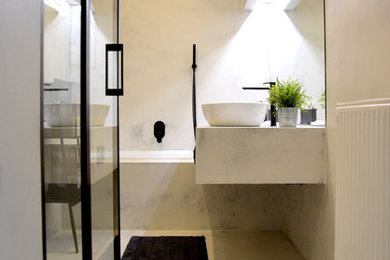 This is an example of a small industrial powder room in Other with open cabinets, black cabinets, a wall-mount toilet, gray tile, grey walls, concrete floors, a vessel sink, concrete benchtops, grey floor and grey benchtops.