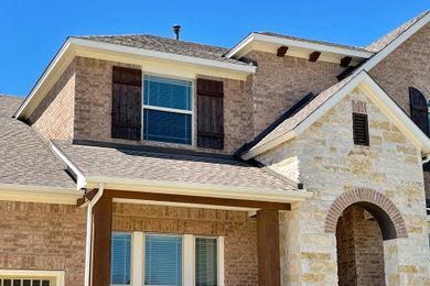 Inspiration for a mid-sized beige two-story stone exterior home remodel in Austin with a shingle roof and a brown roof