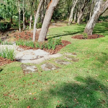 Backyard Tudor revival landscape along a natural area with a stream