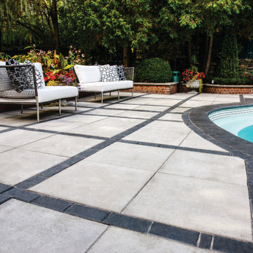 Traditional poolside paradise with grey and black pavers
