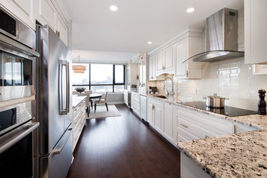 Design ideas for a large traditional galley eat-in kitchen in Ottawa with an undermount sink, raised-panel cabinets, white cabinets, granite benchtops, white splashback, subway tile splashback, stainless steel appliances, dark hardwood floors, a peninsula and brown floor.