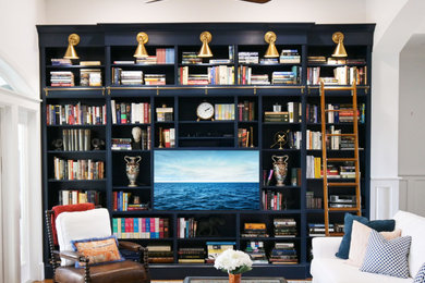 Ejemplo de sala de estar con biblioteca abierta tradicional renovada grande con paredes blancas, suelo de madera en tonos medios y pared multimedia