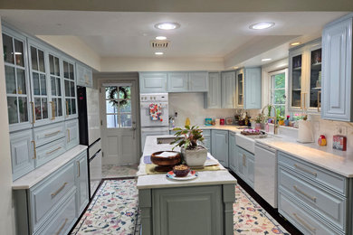 Inspiration for a large timeless u-shaped dark wood floor, brown floor and tray ceiling enclosed kitchen remodel in Cincinnati with a farmhouse sink, raised-panel cabinets, blue cabinets, marble countertops, gray backsplash, marble backsplash, white appliances, an island and gray countertops