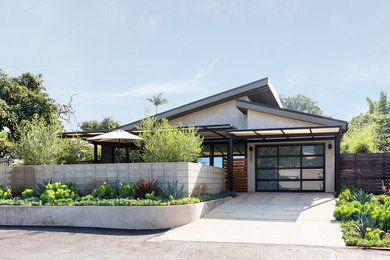 Example of a mid-sized trendy beige one-story stucco house exterior design in San Diego with a metal roof