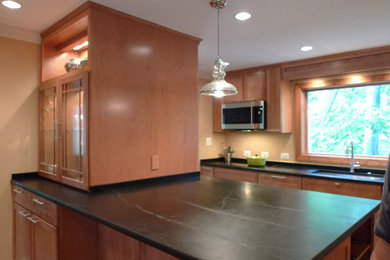Inspiration for a craftsman galley light wood floor and brown floor eat-in kitchen remodel in DC Metro with an undermount sink, shaker cabinets, light wood cabinets, soapstone countertops, beige backsplash, stainless steel appliances, a peninsula and black countertops