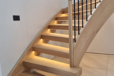 Design ideas for a large contemporary wood curved metal railing staircase in West Midlands with open risers.