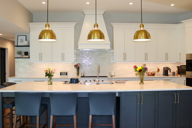 Inspiration for a large contemporary l-shaped dark wood floor, brown floor and vaulted ceiling kitchen remodel in Chicago with an undermount sink, shaker cabinets, yellow cabinets, quartz countertops, white backsplash, ceramic backsplash, stainless steel appliances, an island and white countertops