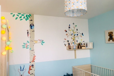 Modelo de dormitorio infantil de 1 a 3 años ecléctico de tamaño medio con paredes azules, suelo de madera clara y suelo beige
