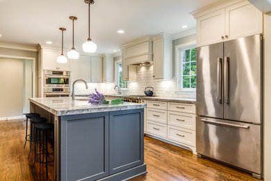 Open concept kitchen - large cottage l-shaped medium tone wood floor and brown floor open concept kitchen idea in Cleveland with an undermount sink, recessed-panel cabinets, white cabinets, granite countertops, white backsplash, subway tile backsplash, stainless steel appliances, an island and multicolored countertops