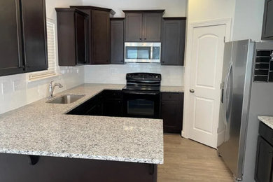 Mid-sized elegant u-shaped medium tone wood floor and brown floor kitchen pantry photo in Charlotte with an undermount sink, shaker cabinets, dark wood cabinets, granite countertops, white backsplash, subway tile backsplash, stainless steel appliances, a peninsula and gray countertops