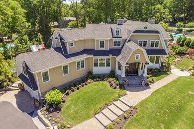 Inspiration for a mid-sized transitional beige two-story vinyl house exterior remodel in New York with a gambrel roof and a shingle roof