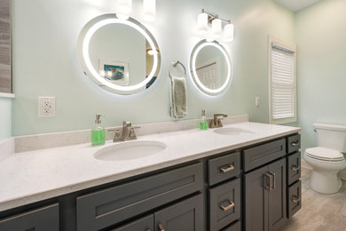 Alcove shower - mid-sized transitional master porcelain tile porcelain tile and double-sink alcove shower idea in Cleveland with shaker cabinets, gray cabinets, a two-piece toilet, an undermount sink, quartz countertops, a hinged shower door and white countertops