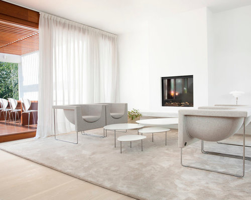 Modelo de salón para visitas abierto, contemporáneo, de tamaño medio, sin televisor, con paredes blancas, suelo de madera clara y estufa de leña