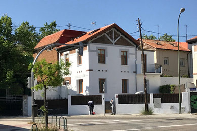 Diseño de fachada de casa blanca clásica renovada de tamaño medio de tres plantas con revestimiento de estuco, tejado a dos aguas y teja