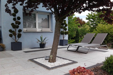 Design ideas for a large contemporary backyard patio in Strasbourg with natural stone pavers.