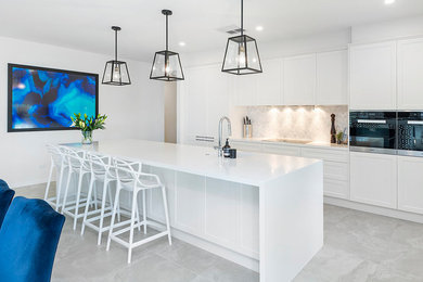 Inspiration for a contemporary galley kitchen in Gold Coast - Tweed with shaker cabinets, white cabinets, grey splashback, stainless steel appliances, with island, grey floor and white benchtop.