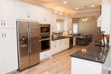 Mid-sized transitional galley porcelain tile and beige floor enclosed kitchen photo in Other with raised-panel cabinets, white cabinets, granite countertops, beige backsplash, porcelain backsplash, stainless steel appliances and a peninsula