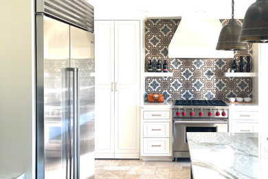 Mid-sized tuscan u-shaped limestone floor and beige floor enclosed kitchen photo in Los Angeles with an undermount sink, recessed-panel cabinets, blue cabinets, solid surface countertops, porcelain backsplash, stainless steel appliances and an island