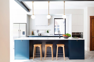 Inspiration for a large contemporary single-wall gray floor kitchen remodel in Montreal with an undermount sink, shaker cabinets, blue cabinets, quartz countertops, white backsplash, quartz backsplash, stainless steel appliances, an island and white countertops