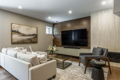 Photo of a mid-sized transitional walk-out basement in Toronto with a home bar, beige walls, medium hardwood floors, a ribbon fireplace, a tile fireplace surround, brown floor and wood walls.