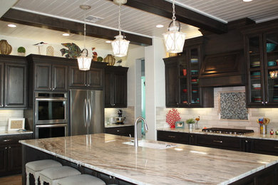 Large beach style u-shaped porcelain tile kitchen photo in Houston with a single-bowl sink, glass-front cabinets, dark wood cabinets, marble countertops, gray backsplash, stone tile backsplash, stainless steel appliances and an island