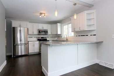 Mid-sized transitional l-shaped dark wood floor eat-in kitchen photo in Wichita with shaker cabinets, white cabinets, granite countertops, white backsplash, subway tile backsplash, stainless steel appliances, a peninsula and a double-bowl sink