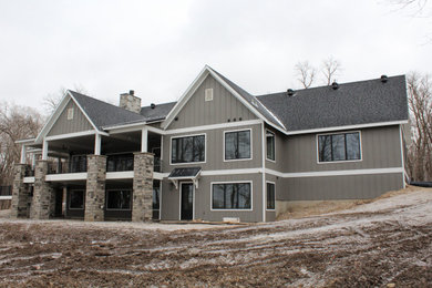Example of a large gray two-story mixed siding and board and batten exterior home design in Other with a mixed material roof and a black roof