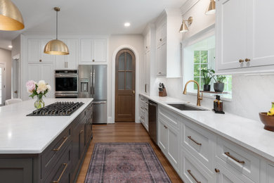 Large transitional l-shaped vinyl floor and brown floor open concept kitchen photo in St Louis with an undermount sink, flat-panel cabinets, white cabinets, quartz countertops, white backsplash, quartz backsplash, stainless steel appliances, an island and white countertops