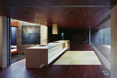 Inspiration for a huge asian single-wall dark wood floor eat-in kitchen remodel in New York with a drop-in sink, flat-panel cabinets, white cabinets, granite countertops, stainless steel appliances and a peninsula