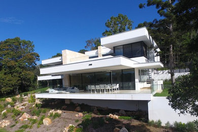 Design ideas for an expansive contemporary three-storey white house exterior in Brisbane with stone veneer.