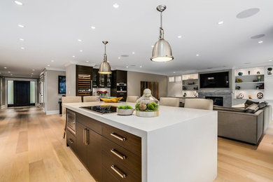 Photo of a large contemporary l-shaped open plan kitchen in Vancouver with quartz benchtops, light hardwood floors, stainless steel appliances, flat-panel cabinets, dark wood cabinets, window splashback and with island.