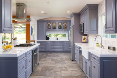 Elegant u-shaped kitchen photo in San Diego with a farmhouse sink, raised-panel cabinets, white backsplash, stainless steel appliances and a peninsula
