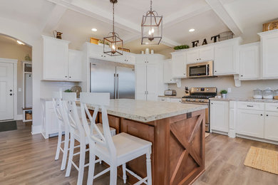 Large cottage u-shaped medium tone wood floor and brown floor open concept kitchen photo in Grand Rapids with a drop-in sink, shaker cabinets, white cabinets, beige backsplash, porcelain backsplash, stainless steel appliances, an island and beige countertops