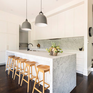 Inspiration for a contemporary galley open plan kitchen in Melbourne with a double-bowl sink, shaker cabinets, white cabinets, grey splashback, marble splashback, dark hardwood floors, with island and brown floor.