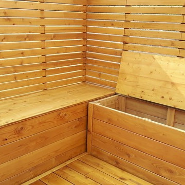 Terrasse mit Sichtschutz, sowie Blumenkübeln und Sitzbänken in Lärche