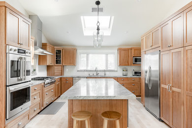This is an example of a large transitional u-shaped eat-in kitchen in San Francisco with shaker cabinets, white splashback, subway tile splashback, stainless steel appliances and with island.