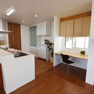 他の地域のモダンスタイルのおしゃれなホームオフィス・仕事部屋 (白い壁、合板フローリング、暖炉なし、造り付け机、茶色い床) の写真