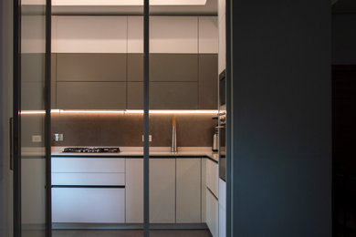 Foto di una cucina a L minimal chiusa e di medie dimensioni con lavello a doppia vasca, ante lisce, ante bianche, top in quarzo composito, paraspruzzi grigio, paraspruzzi in gres porcellanato, elettrodomestici da incasso, pavimento in gres porcellanato, pavimento grigio e top bianco